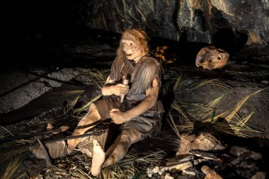 Grotta Nera 'daki Orta Paleolitik bir sahnenin yeniden inşası. Eski vahşi insanların ilkel kabilesi hayvan derisi ve taş baltalar mağarada kalan şenlik ateşinde kızartılmış et yiyorlar. Neandertaller. Buzul çağı. Basescu Trieste