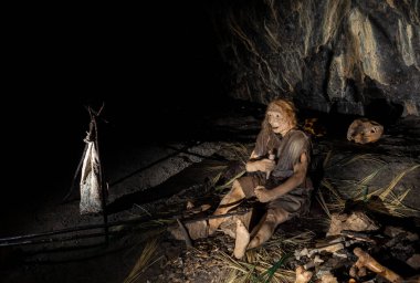 Grotta Nera 'daki Orta Paleolitik bir sahnenin yeniden inşası. Eski vahşi insanların ilkel kabilesi hayvan derisi ve taş baltalar mağarada kalan şenlik ateşinde kızartılmış et yiyorlar. Neandertaller. Buzul çağı. Basescu Trieste