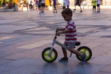 Bilbao, İspanya - 02 Ağustos 2022: Bilbao Meydanı 'nda bisiklete binen çocuk