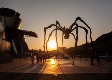 Bilbao, İspanya - 02 Ağustos 2022: Louise Bourgeois 'in günbatımında Guggenheim Müzesi' nin yanındaki Mamam adlı Örümcek heykeli