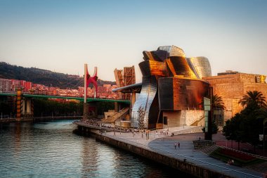Bilbao, İspanya - 02 Ağustos 2022: Günbatımı modern ve çağdaş sanat Guggenheim Müzesi ve La Salve Köprüsü