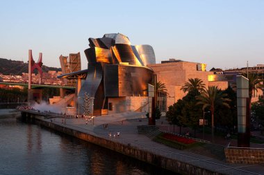 Bilbao, İspanya - 2 Ağustos 2022: Amerikan mimar Frank Gehry tarafından tasarlanan ve Ekim 1997 'de hizmete giren modern ve çağdaş sanat eseri Guggenheim Müzesi' nin günbatımı.