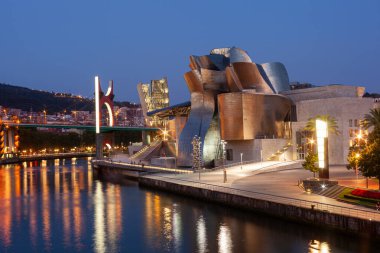Bilbao, İspanya - 02 Ağustos 2022: Günbatımı modern ve çağdaş sanat Guggenheim Müzesi ve La Salve Köprüsü