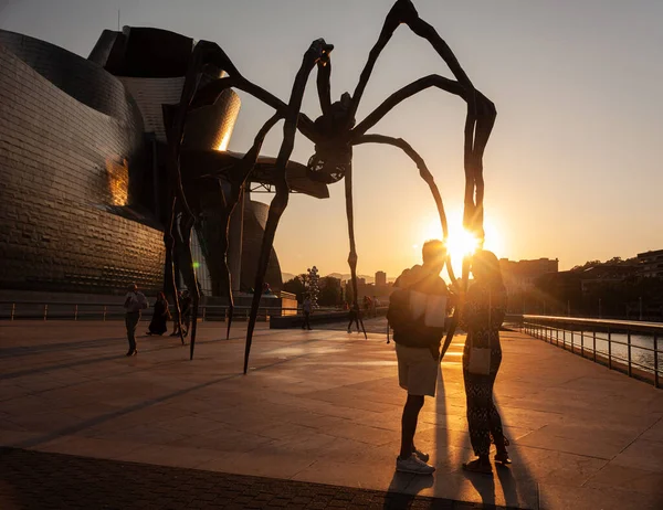 Bilbao, İspanya - 02 Ağustos 2022: Günbatımında, Louise Bourgeois 'in Guggenheim Müzesi' ndeki Mamam adlı heykelinin yanında bir çift turist selfie çekiyor.