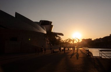 Bilbao, İspanya - 02 Ağustos 2022: Guggenheim Müzesi 'nin gün batımında Louise Bourgeois' in dev örümcek çizimlerinin yanında