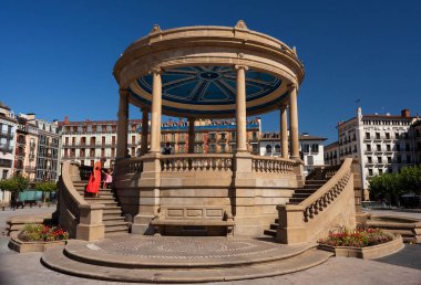 Pamplona, İspanya - 2 Ağustos 2022: İspanya 'nın Pamplona kentindeki Kale Meydanı' ndaki küçük kızıyla birlikte kırmızı elbise giyen kadın
