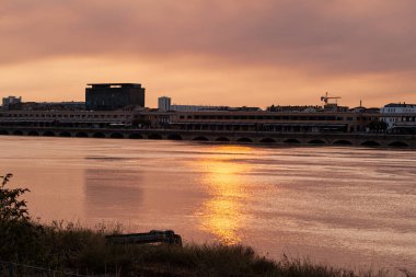 Gün batımında Garonne nehri ve nehir kenarındaki çimlerin manzarası.