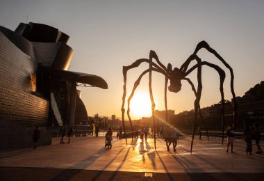 Bilbao, İspanya - 02 Ağustos 2022: Louise Bourgeois 'in günbatımında Guggenheim Müzesi' nin yanındaki Mamam adlı Örümcek heykeli