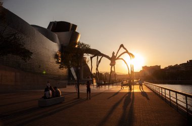 Bilbao, İspanya - 02 Ağustos 2022: Guggenheim Müzesi 'nin gün batımında Louise Bourgeois' in dev örümcek çizimlerinin yanında