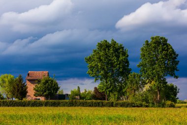 Geleneksel İtalyan çiftlik evi yeşil çimenler ve güzel bulutlu gökyüzü ile çevrili. Köy manzarası.