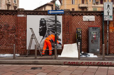 Milan, İtalya - 21 Nisan 2023: İşçiler duvarlara 2023 tarihli Moncler koleksiyonunu gösteren posterler asıyorlar
