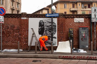 Milan, İtalya - 21 Nisan 2023: İşçiler duvarlara 2023 tarihli Moncler koleksiyonunu gösteren posterler asıyorlar