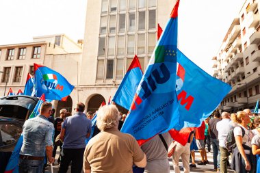 Trieste, İtalya - 03 Eylül 2022: Wartsila grubundan işçilerin işten çıkarılmasına karşı düzenlenen gösteri sırasında İtalyan UIL ve UILM Birliği bayraklarıyla protestocular.
