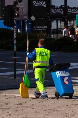 Trieste, İtalya - 30 Eylül 2023: Sarı üniformalı bir adam çöp topluyor, sokakları temizliyor. Çöpçü, çöpçü, çöpçü, Ashman.