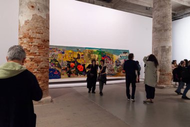 Venedik, İtalya - 17 Nisan 2024: Venedik bienalinin 60. uluslararası sanat sergisi boyunca ziyaretçiler her yerde yabancılar, Arsenal 'de Stranieri Ovunque, arka planda Bordadoras de Isla Negra' nın sanat eserleri