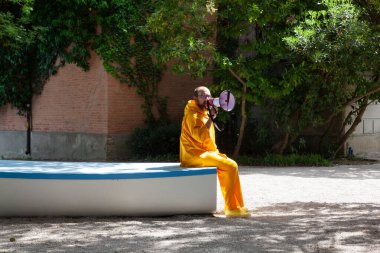 Venedik, İtalya - 20 Nisan 2024: 60. Venedik Bienali 'nin açılışı sırasında Giardini' de turuncu tulumlu ve megafonlu aktörün görüntüsü