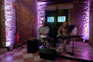 Venedik, İtalya - 19 Nisan 2024: 60. Venedik Bienali 'nde Umman Sultanlığı Pavyonu' nun açılışında perküsyon ve Kanun çalan bir çift müzisyen