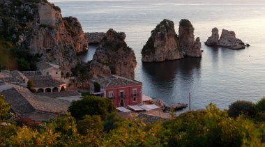 Tonnara 'da kumsal ve kayalık bir uçurum, Trapani. Kumsal sakin ve su berrak.