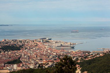 Trieste şehrinin hava görüntüsü ve liman gemileri, limana demirlemiş büyük yolcu feribotları.