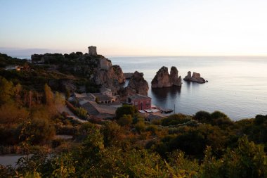 Tonnara 'da kumsal ve kayalık bir uçurum, Trapani. Kumsal sakin ve su berrak.