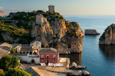 Tonnara 'da kumsal ve kayalık bir uçurum, Trapani. Kumsal sakin ve su berrak.