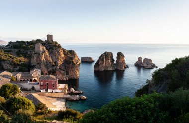 Tonnara 'da kumsal ve kayalık bir uçurum, Trapani. Kumsal sakin ve su berrak.