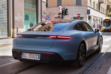Milan, Italy- 22 Haziran 2024: Neptun Blue Porsche Taycan 4S Spor Turizm elektrikli arabası Milano caddesinde