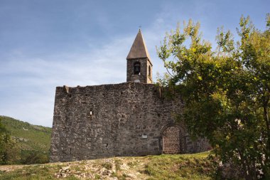 Slovenya 'nın Primorska ve Istria kentlerindeki Karst kıyısında Hrastovlje' de yüksek bir taş duvar ve savunma kulesi ile çevrili eski bir ortaçağ kilisesi manzarası