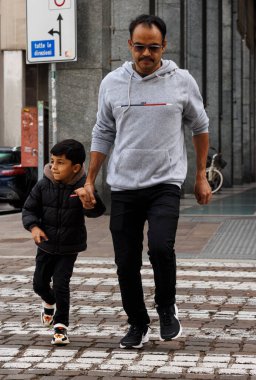 Mantova, İtalya - 14 Eylül 2024: Bir baba ve küçük çocuğu el ele bir yaya geçidinde karşıya geçtiler.