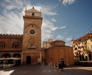 Mantova, Italy - September 15, 2024: The clocktower in Piazza delle Erbe with historical palaces and church clipart