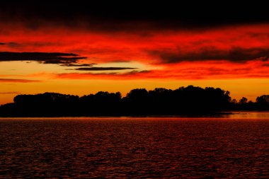 İtalya, Mantua 'daki Mincio nehri üzerinde bulutlu turuncu gün batımı