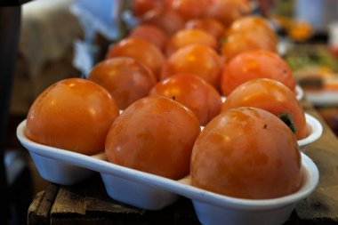 Kırmızı hurmalarla dolu beyaz tepsilerin yakın çekimleri canlı renklerini ve tazeliklerini sergiliyor.
