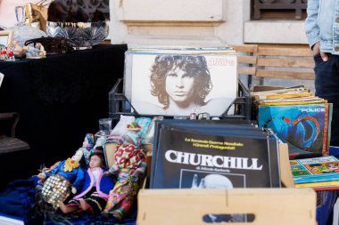 Trieste, İtalya - 29 Eylül 2024: Jim Morrison 'ın görüntüsü ve Churchill hakkında bir kitabın yer aldığı, bir sokak pazarında kitap ve vinil plaklarla dolu kutular.
