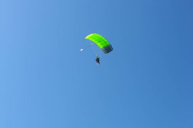 Bovec, Slovenya - 17 Temmuz 2025: Yeşil paraşütlü bir paraglider, arka planda mavi gökyüzü bulunan Slovenya 'nın Kanin kentine iniyor.