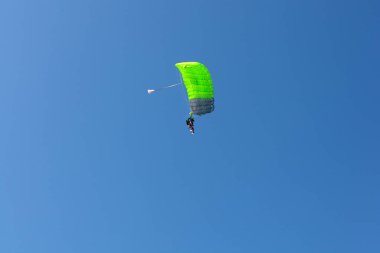 Bovec, Slovenya - 17 Temmuz 2025: Yeşil paraşütlü bir paraglider, arka planda mavi gökyüzü bulunan Slovenya 'nın Kanin kentine iniyor.