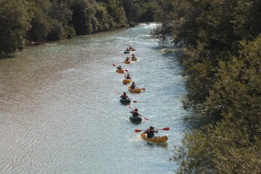 Bovec, Slovenya - 18 Temmuz 2025: Yaz mevsiminde güzel turkuaz Soca nehrinde sporcu kanoları