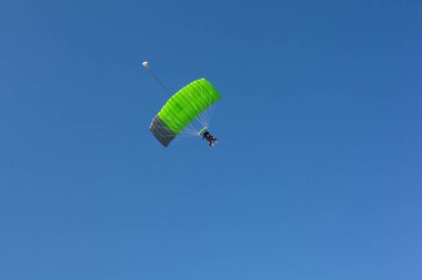 Yeşil paraşütlü bir paraglider arka planda mavi gökyüzü olan Slovenya 'nın Kanin kentine iniyor..