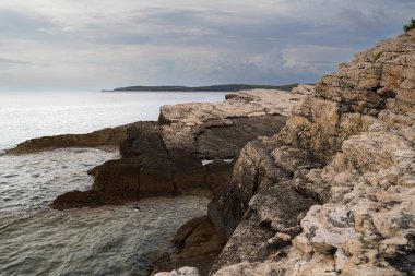 Hırvatistan 'ın Istria kentindeki Medulin belediyesindeki Premantura yarımadasındaki Kamenjak Ulusal Parkı' nın engebeli kireçtaşı manzarası yaz mevsiminde