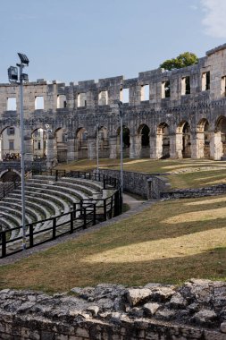 Hırvatistan 'ın Pula kentindeki antik miras. Antik Roma arenasının kemerleri. Tarihi amfi tiyatronun ayrıntıları, mavi arka plandaki yüksek duvarların geniş açılı görüntüsü..