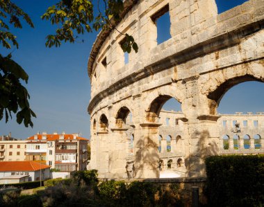 Hırvatistan 'ın Pula kentindeki antik miras. Antik Roma arenasının kemerleri. Tarihi amfi tiyatronun ayrıntıları, mavi arka plandaki yüksek duvarların geniş açılı görüntüsü..