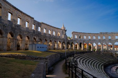 Hırvatistan 'ın Pula kentindeki antik miras. Antik Roma arenasının kemerleri. Tarihi amfi tiyatronun ayrıntıları, mavi arka plandaki yüksek duvarların geniş açılı görüntüsü..