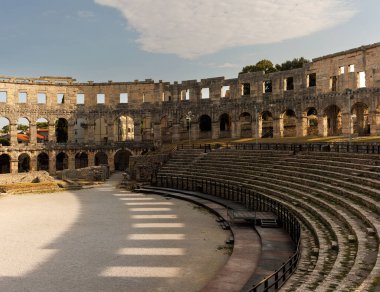 Hırvatistan 'ın Pula kentindeki antik miras. Antik Roma arenasının kemerleri. Tarihi amfi tiyatronun ayrıntıları, mavi arka plandaki yüksek duvarların geniş açılı görüntüsü..