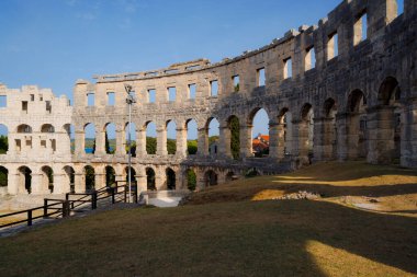 Hırvatistan 'ın Pula kentindeki antik miras. Antik Roma arenasının kemerleri. Tarihi amfi tiyatronun ayrıntıları, mavi arka plandaki yüksek duvarların geniş açılı görüntüsü..