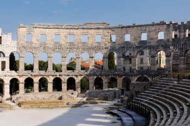 Hırvatistan 'ın Pula kentindeki antik miras. Antik Roma arenasının kemerleri. Tarihi amfi tiyatronun ayrıntıları, mavi arka plandaki yüksek duvarların geniş açılı görüntüsü..