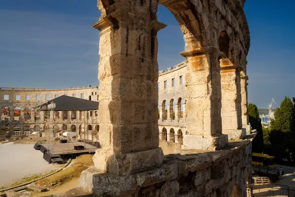 Hırvatistan 'ın Pula kentindeki antik miras. Antik Roma arenasının kemerleri. Tarihi amfi tiyatronun ayrıntıları, mavi arka plandaki yüksek duvarların geniş açılı görüntüsü..