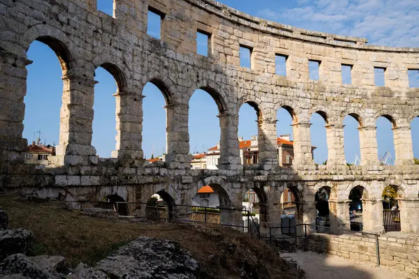 Hırvatistan 'ın Pula kentindeki antik miras. Antik Roma arenasının kemerleri. Tarihi amfi tiyatronun ayrıntıları, mavi arka plandaki yüksek duvarların geniş açılı görüntüsü..
