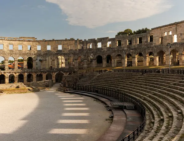 Hırvatistan 'ın Pula kentindeki antik miras. Antik Roma arenasının kemerleri. Tarihi amfi tiyatronun ayrıntıları, mavi arka plandaki yüksek duvarların geniş açılı görüntüsü..