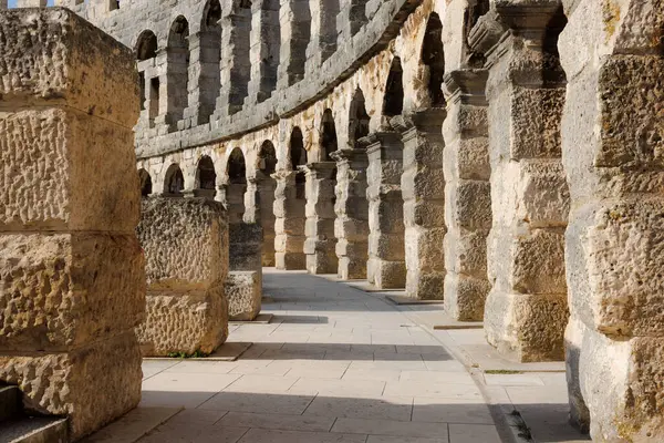 Hırvatistan 'ın Pula kentindeki antik miras. Antik Roma arenasının kemerleri. Tarihi amfi tiyatronun ayrıntıları, mavi arka plandaki yüksek duvarların geniş açılı görüntüsü..