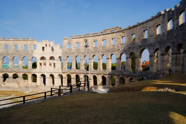 Hırvatistan 'ın Pula kentindeki antik miras. Antik Roma arenasının kemerleri. Tarihi amfi tiyatronun ayrıntıları, mavi arka plandaki yüksek duvarların geniş açılı görüntüsü..
