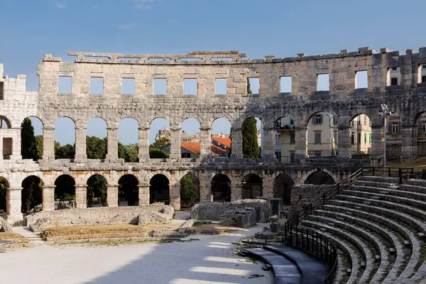 Hırvatistan 'ın Pula kentindeki antik miras. Antik Roma arenasının kemerleri. Tarihi amfi tiyatronun ayrıntıları, mavi arka plandaki yüksek duvarların geniş açılı görüntüsü..